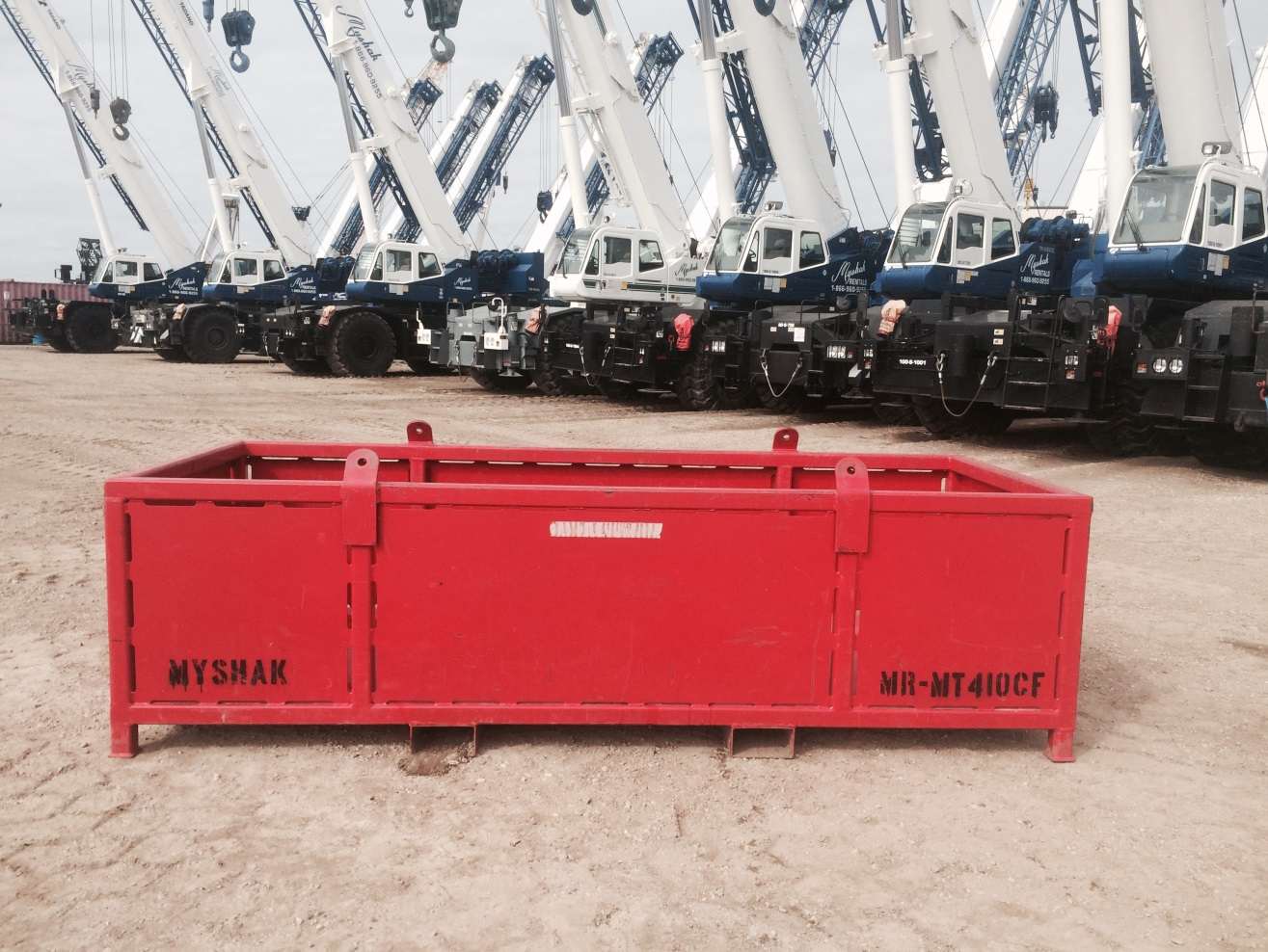 Large material basket on ground with cranes in background