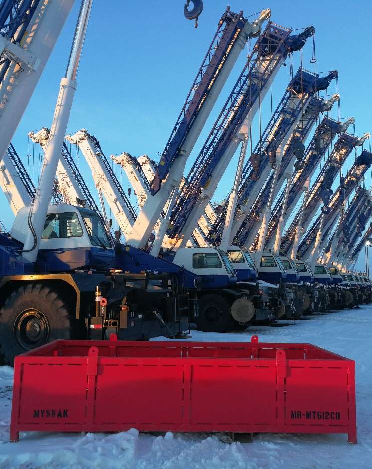 Medium red material basket on snow with cranes in background