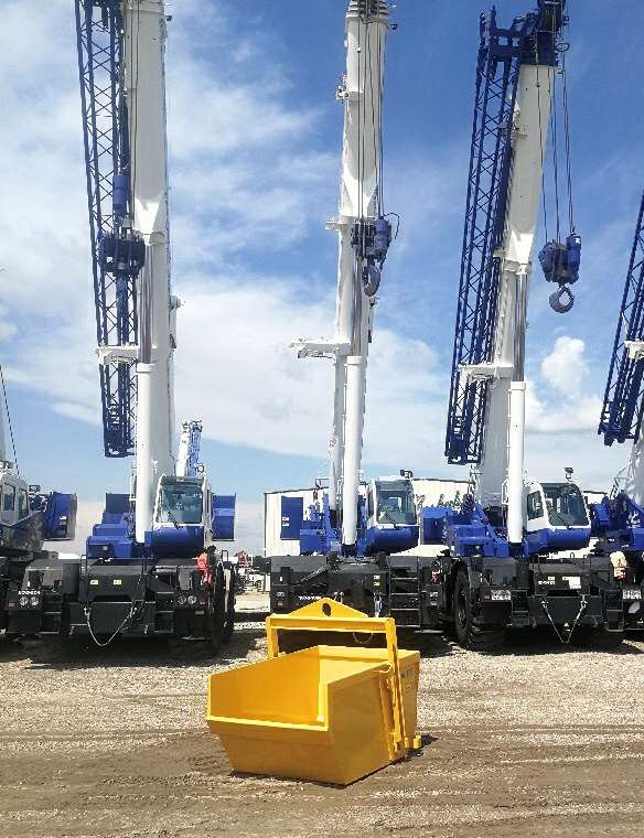 Yellow self dumping bin with cranes behind.