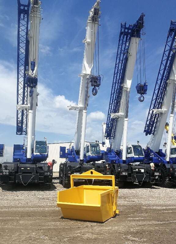 Yellow self dumping bin with cranes behind.